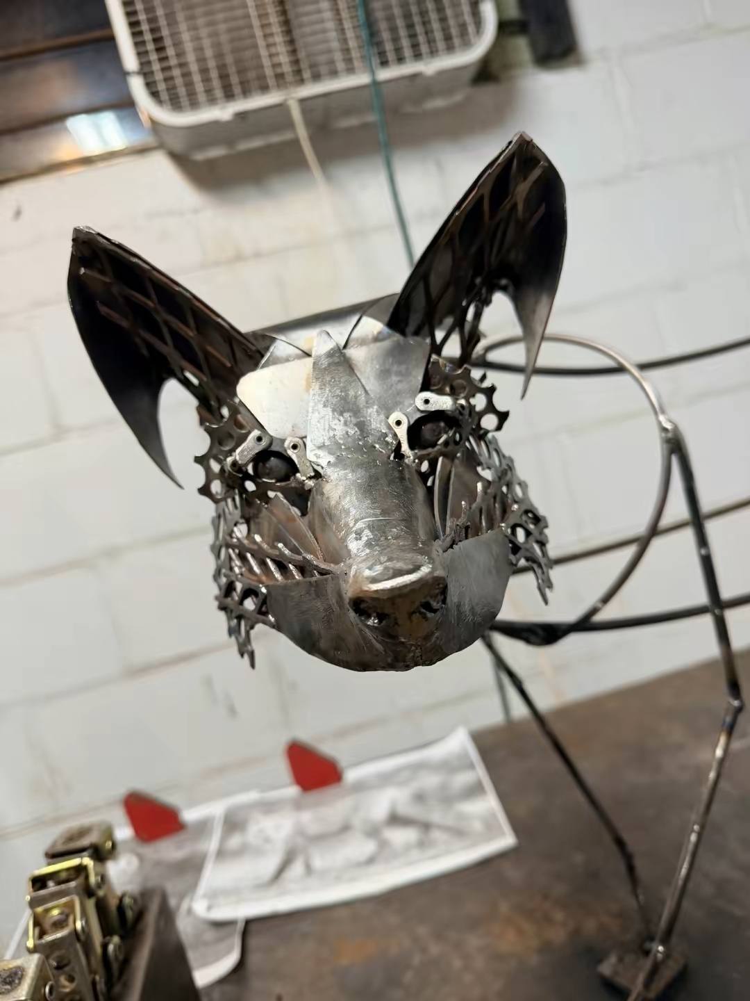 Franklin, a welded fox sculpture in progress, face viewed head-on showing the gear-built eyes and muzzle